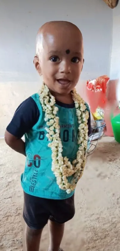 Smiling child with flower garland indoors.