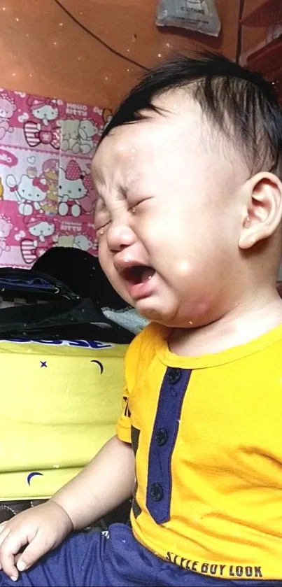 Adorable baby in yellow shirt crying, showcasing innocence.