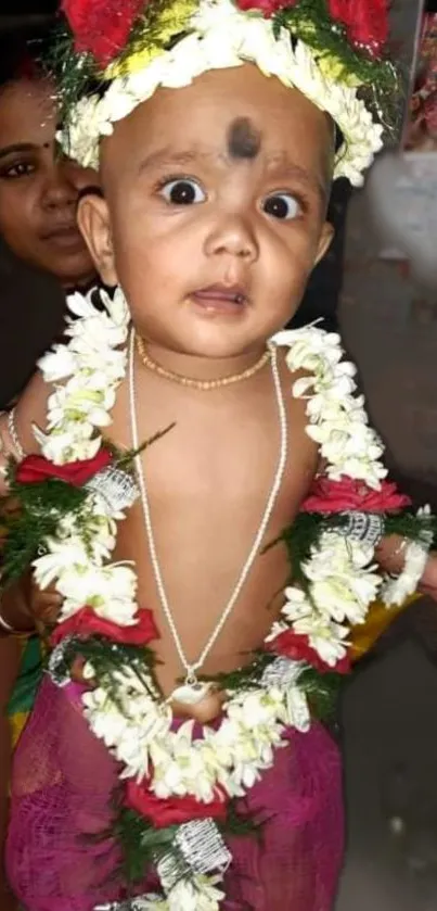 Adorable baby with floral garland and traditional jewelry.