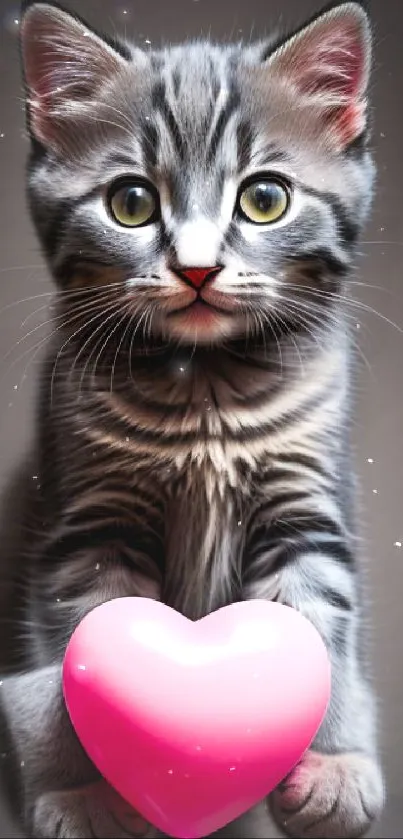 Gray tabby kitten holding a pink heart balloon.