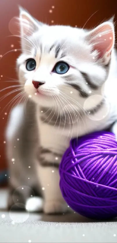 A cute kitten with a purple yarn ball, displaying blue eyes and playful pose.