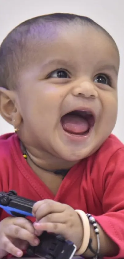 Adorable baby laughing in a red sweater, holding a toy.