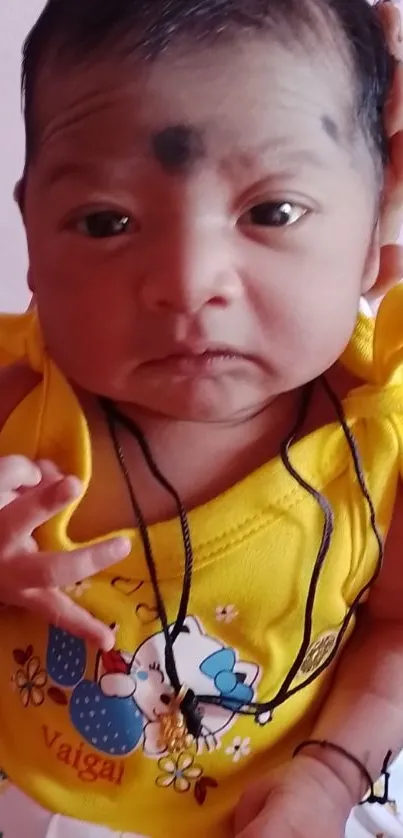 Adorable newborn wearing a yellow dress, looking charming and happy.