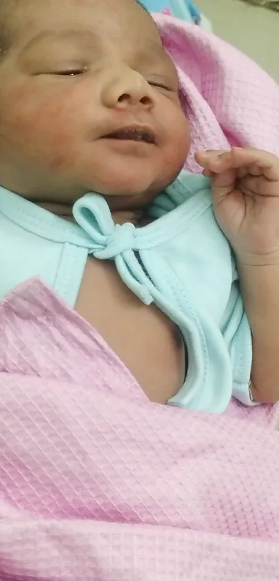 Adorable newborn baby in a pink blanket, sleeping peacefully.