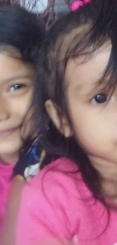 Two smiling siblings in pink sweaters capturing a heartwarming moment.