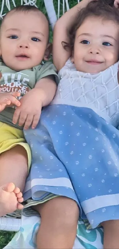 Two siblings smiling while on a swing outdoors.