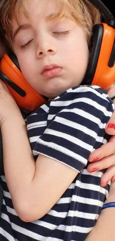 Child sleeping with headphones and striped shirt.