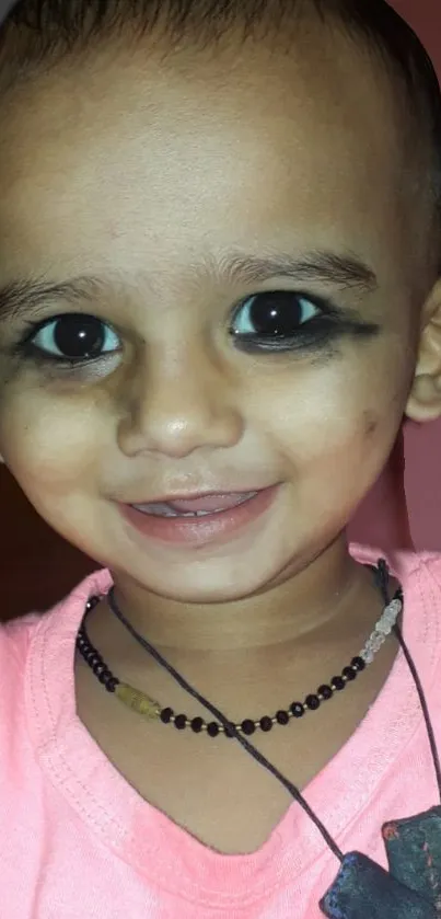 Adorable baby with big smile and bright eyes in a pink shirt.