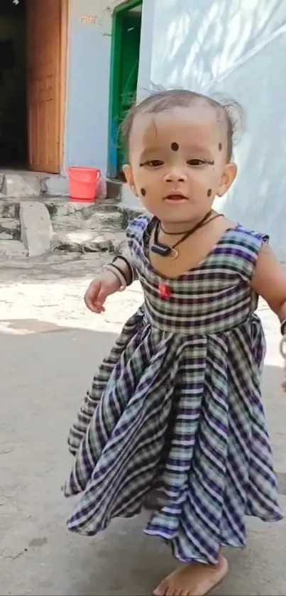 Adorable toddler in a checkered dress outdoors.