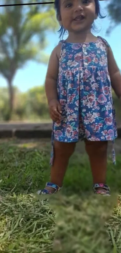 Adorable toddler with floral dress outdoors, smiling gleefully.