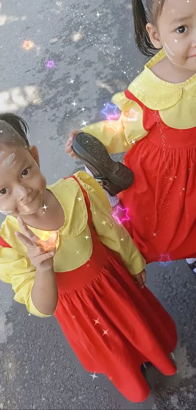 Two adorable kids in red dresses posing playfully.