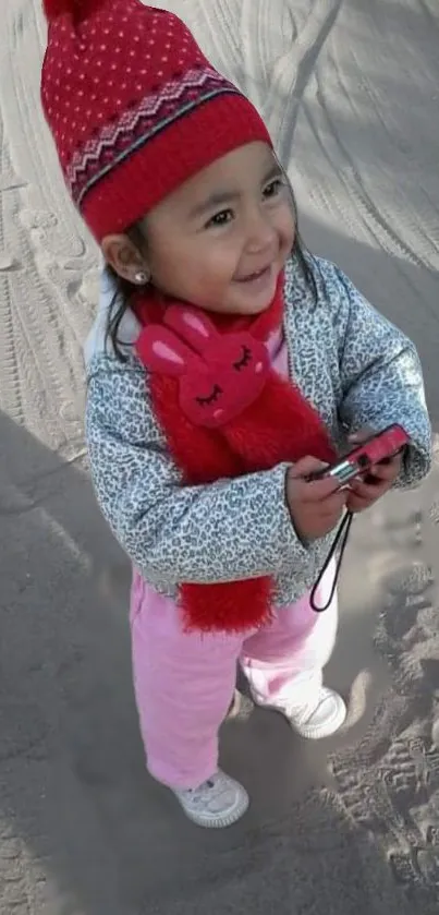 Cute child in winter clothes with red hat smiling joyfully.