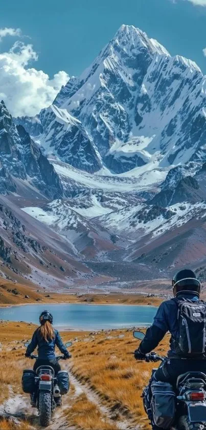 Motorcyclists ride towards snow-capped mountains under clear sky.