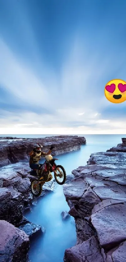 Motorcyclist rides on rugged coastline under a vibrant blue sky.