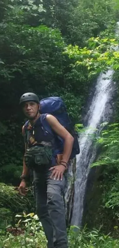 Hiker standing beside a scenic waterfall amidst lush greenery.