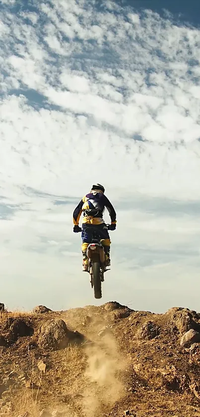 Motorcycle jumping off a dirt ramp under a cloudy sky.