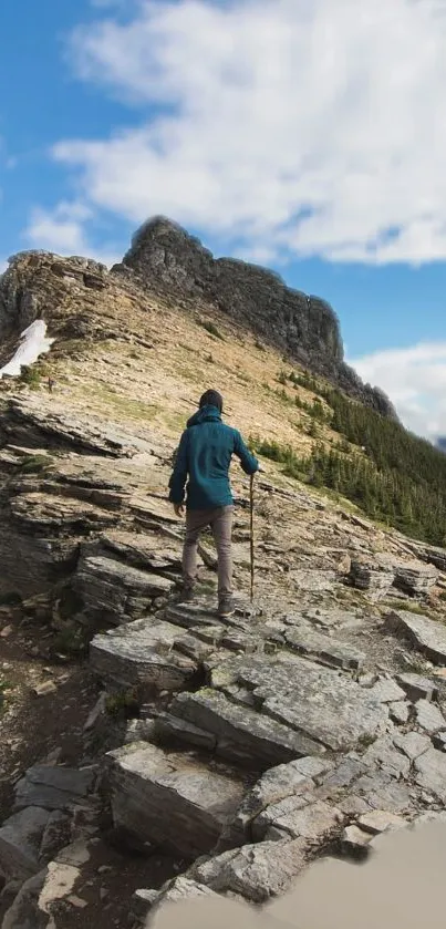 Person hiking on rocky mountain trail under blue skies.