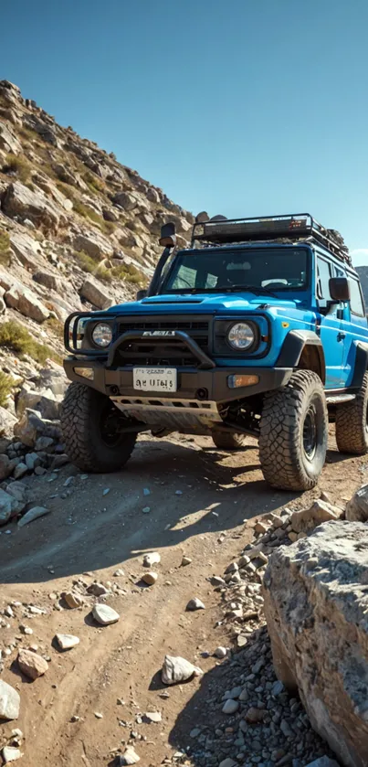 Blue Jeep on a rocky mountain trail under clear skies.