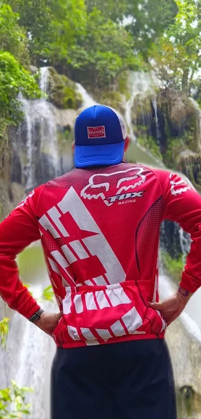 Explorer standing in front of waterfalls with lush greenery.