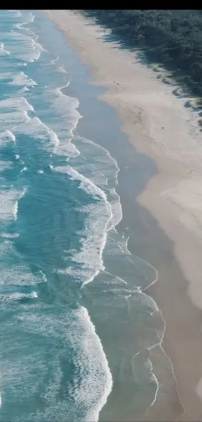 Aerial view of turquoise ocean waves gently crashing on a sandy beach.