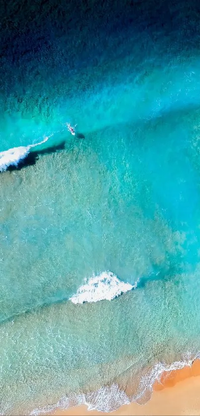 Aerial view of ocean waves meeting a sandy beach with turquoise water.