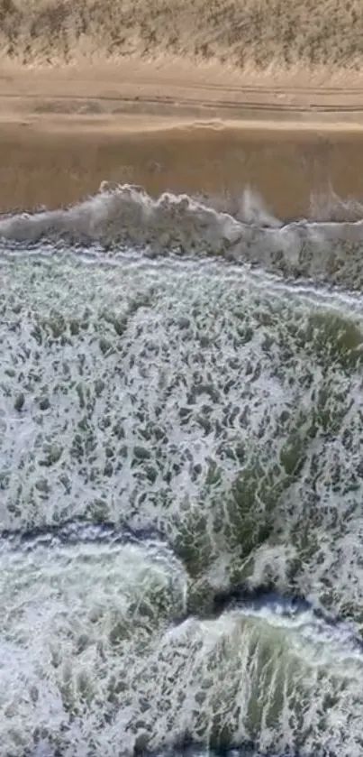 Aerial view of ocean waves crashing on a sandy beach.