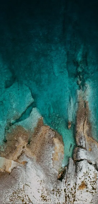 Aerial view of ocean with turquoise water and rocky shore.