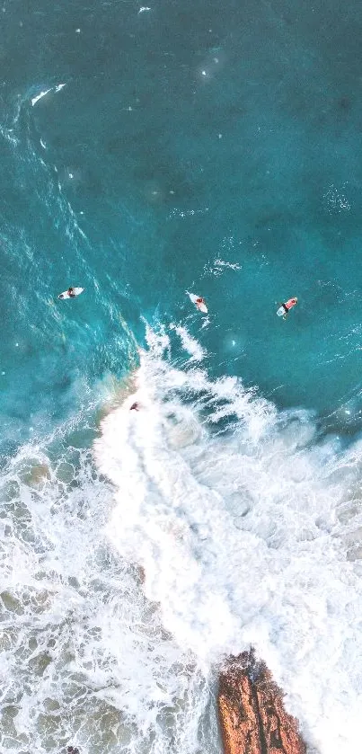 Aerial shot of ocean waves with surfers riding on turquoise waters.