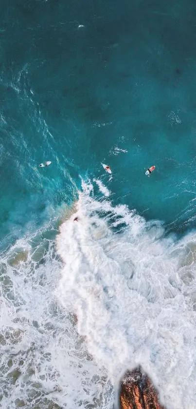Aerial view of surfers riding ocean waves near rocky coastline.