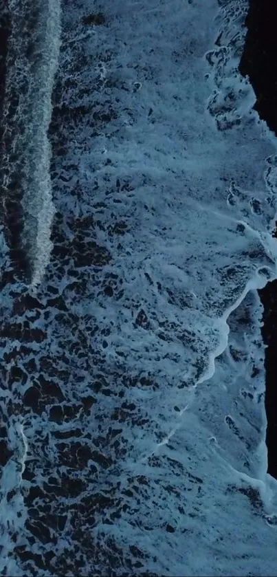 Aerial view of ocean waves crashing against the shore at night.