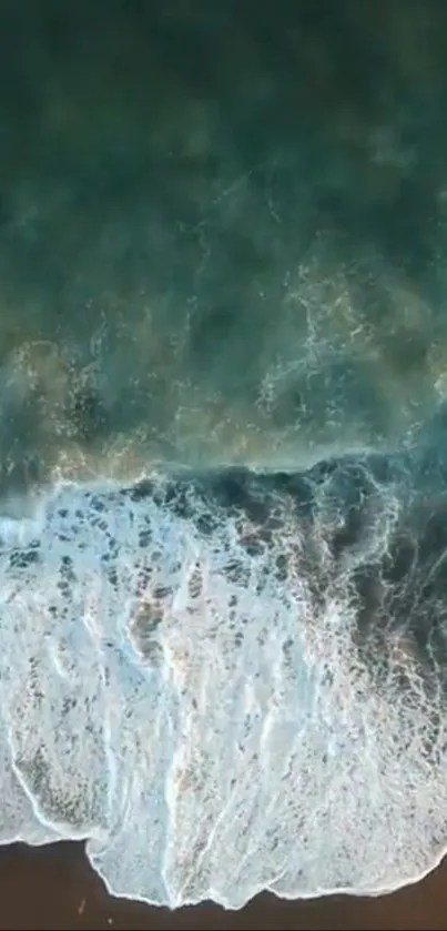 Aerial view of ocean waves crashing onto a sandy beach.