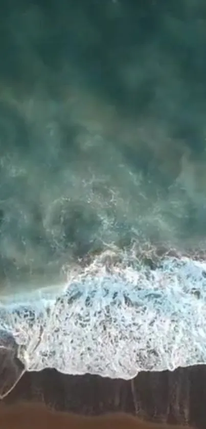 Aerial view of ocean waves crashing on a sandy beach with teal waters.