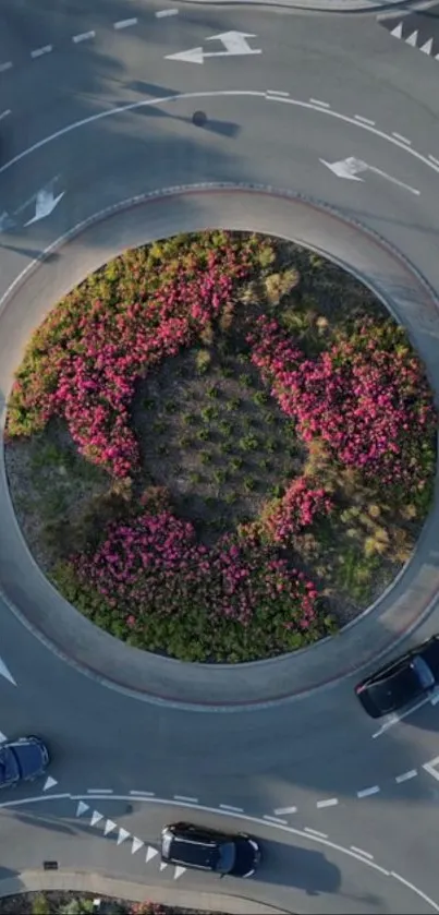 Aerial view of a roundabout with colorful flowers and cars.