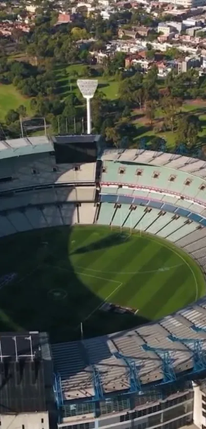 Aerial view of stadium with green field and surrounding trees.