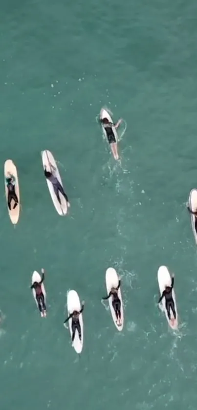 Aerial view of surfers lined up on aqua waves.