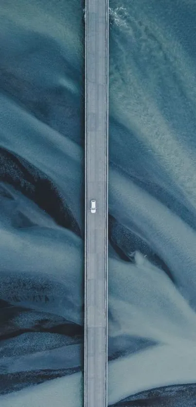 Aerial view of a car crossing a bridge over swirling blue waters.