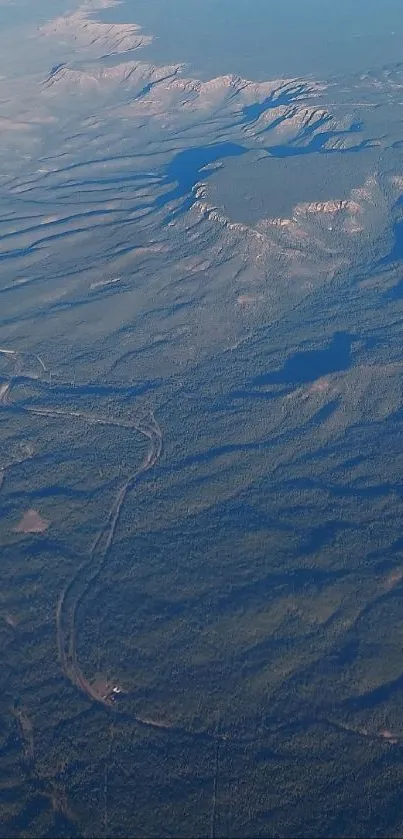 Aerial view from an airplane showing mountain ranges and vast blue sky.