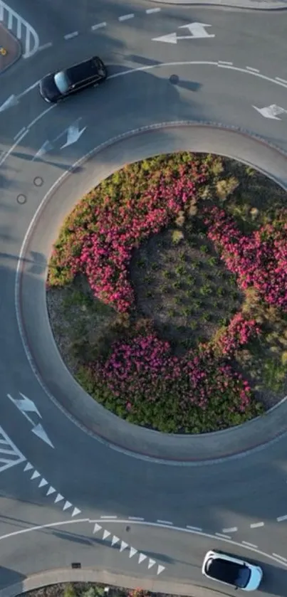 Aerial view of a landscaped roundabout with cars and floral patterns.