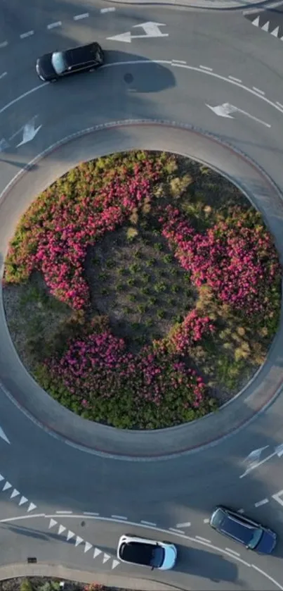 Aerial view of a roundabout with cars and colorful flowers.