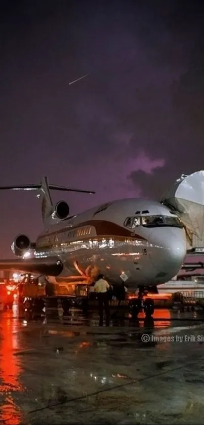 Airplane parked at night airport with reflections and purple sky.