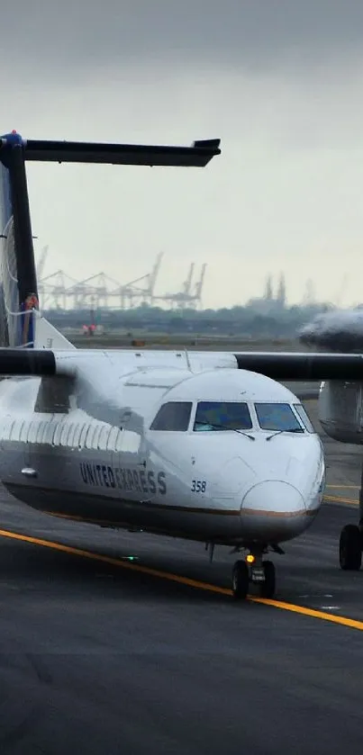 Airplane positioned on airport runway, with overcast sky background.