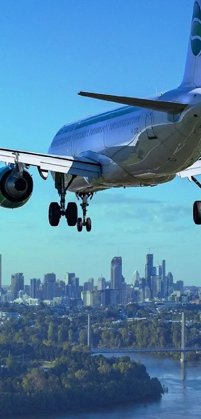 Airplane flying over a city with a river view and clear blue sky.