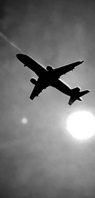 Airplane silhouette flying across the bright sun in a monochrome sky.