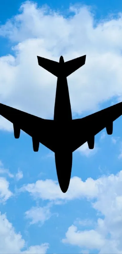 Silhouette of airplane against a blue sky with white clouds.