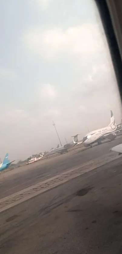 Airport scene from airplane window with multiple parked planes.