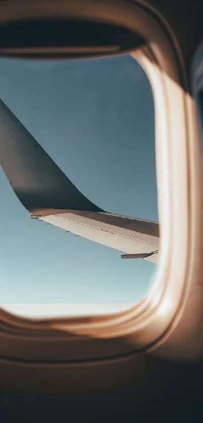 Airplane wing seen through a window against a blue sky.