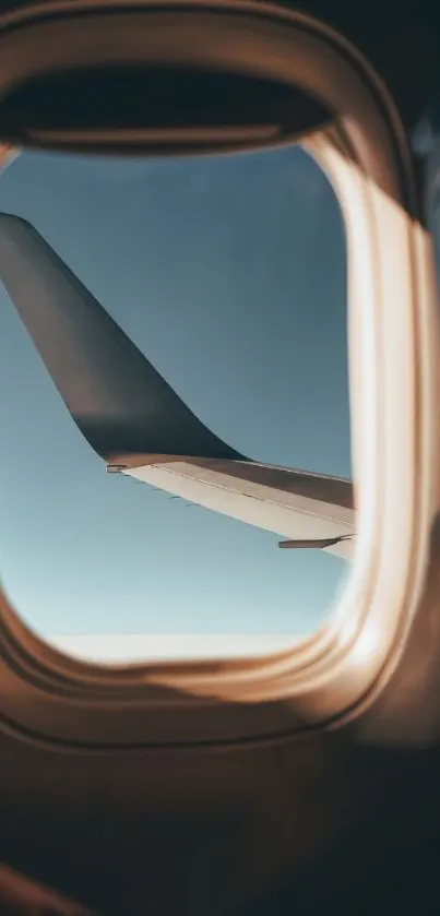 Airplane wing viewed through a window with a clear blue sky in the background.