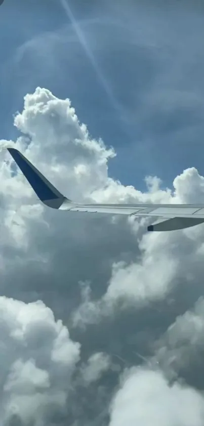 Airplane wing above fluffy clouds and blue sky.