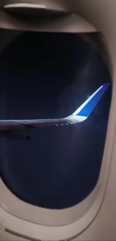 View of airplane wing at night from a window, with a dark blue sky backdrop.