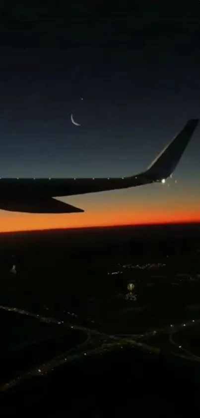 Silhouette of an airplane wing at sunset with a crescent moon in the sky.